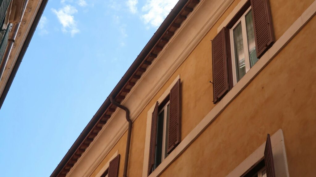 Facciata di un palazzo romano con persiane in legno, affitto breve o canone concordato a Roma