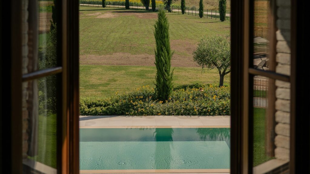 Vista dalla finestra su piscina a sfioro e campagna toscana, villa di lusso candidata ad Airbnb Luxe