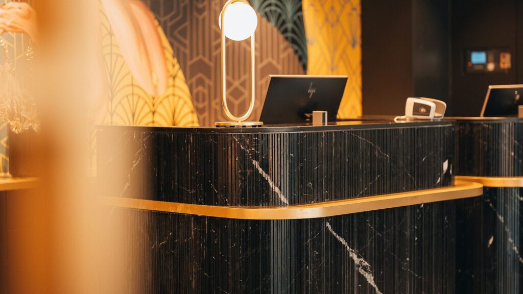 Reception di un hotel boutique con bancone in marmo nero, dettagli in ottone